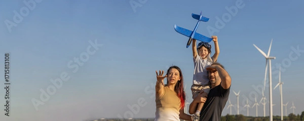 Fototapeta Family with son walking on field on wind farm. Happy Family and son playing at the Wind turbines generating electricity. Family time together.