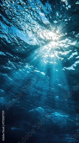 Obraz Sunbeams pierce deep blue ocean water, creating a dramatic underwater light show with textured surface and dark depths