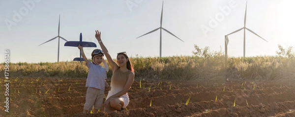 Fototapeta Family with son walking on field on wind farm. Happy Family and son playing at the Wind turbines generating electricity. Family time together.