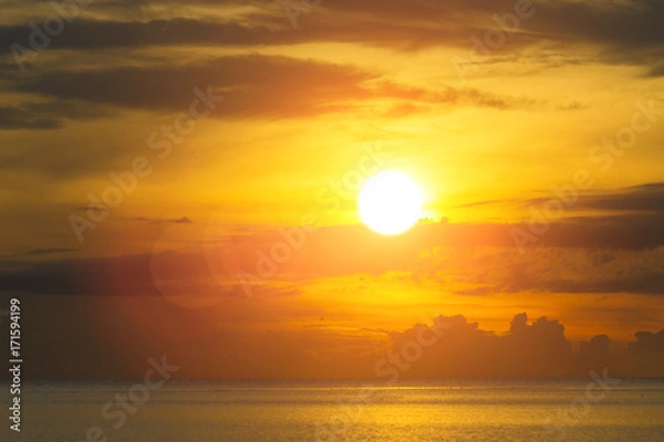 Fototapeta The sun shines through the clouds at dawn on the shore of the Gulf of Thailand.