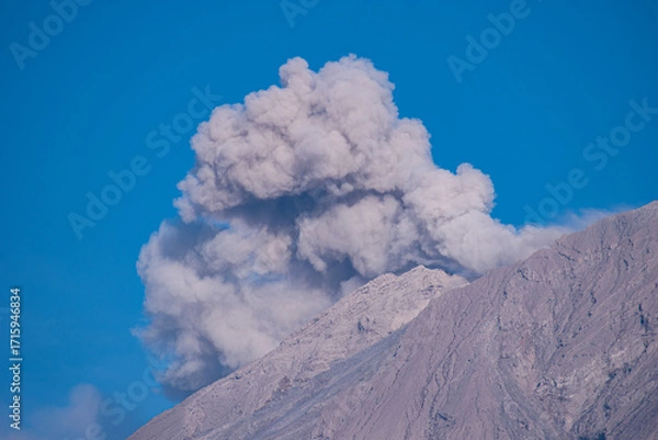 Fototapeta Close up view of Mount Semeru’s summit spewing smoke and volcanic ash under a bright blue sky, showcasing the natural beauty and rugged details of this powerful Indonesian volcano.