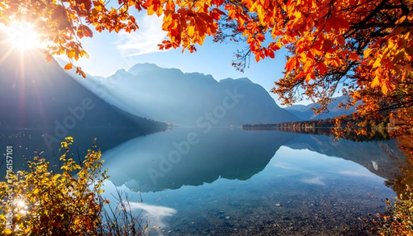 Fototapeta Serene mountain lake reflecting autumn foliage and sun rays on a clear day