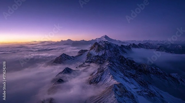 Fototapeta Snow-capped mountain peaks rising above a sea of clouds at twilight