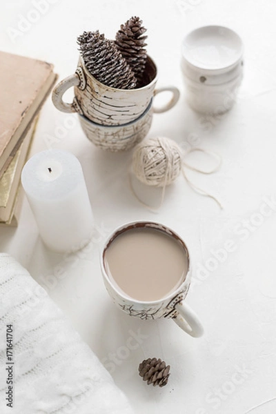 Fototapeta A cup of coffee with milk and a cosy wool plaid on the white concrete table in the morning. Winter or autumn season.