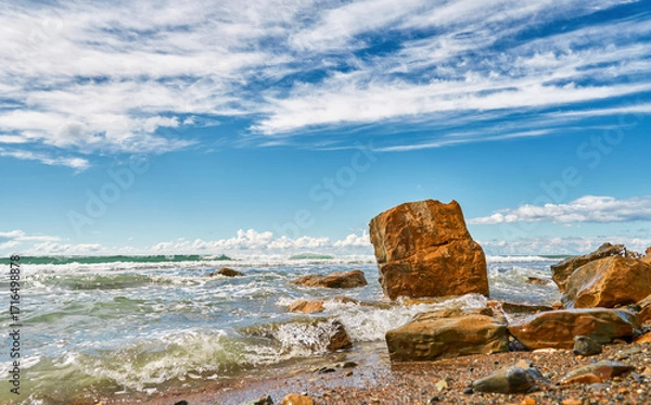 Fototapeta rocky shore with broken rock is washed by the ocean surf, copy space concept about an eco-friendly lifestyle and sustainable ecosystem development, backdrop for an advertisement for natural products