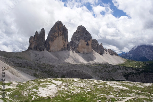 Fototapeta Majestic Dolomites mountain range with towering peaks and lush green valley under a dramatic cloudy sky