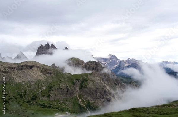 Fototapeta  Majestic Dolomite mountains shrouded in mist with lush green valleys and dramatic cloud formations in the background