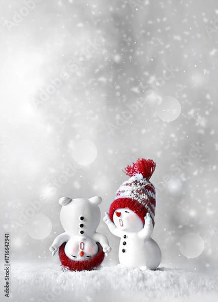 Fototapeta Two little snowmen in caps on snow in the winter. Background with a funny snowmen. Christmas card.