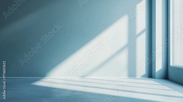 Fototapeta Light streams through a window onto a wall and floor in an empty room.