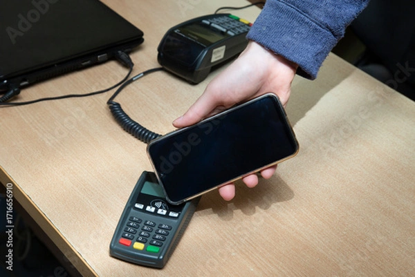 Fototapeta Contactless payment using a smartphone instead of a payment card.