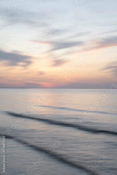 Fototapeta A dreamy, impressionistic paint like blurred sea sunset background with gently soft pastel colours. Vertical photo.