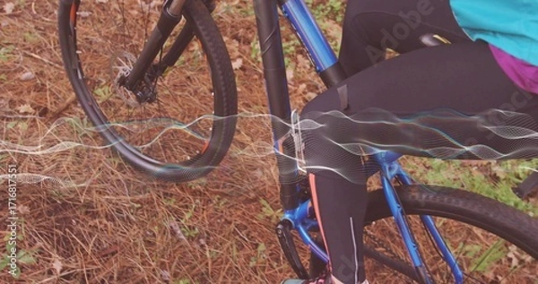 Fototapeta Adult cyclist riding on forest trail in tight athletic wear, with blue bicycle and waveform overlay