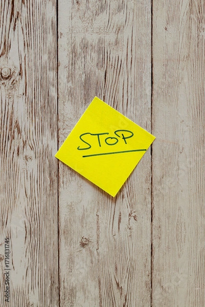 Fototapeta Yellow sticky note with stop word on wooden background