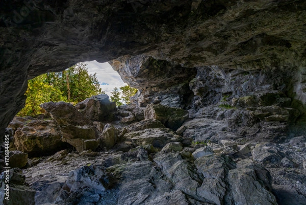 Obraz Cave entrance on Flowerpot Island in Ontario's Bruce Peninsula, showcasing rugged rock formations amidst lush greenery.