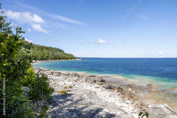 Obraz Picturesque shoreline of Flowerpot Island in Ontario, with vibrant blue waters and lush greenery under a clear sky.