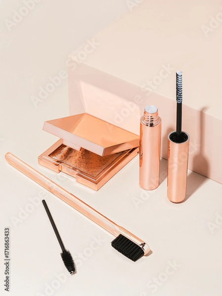 Fototapeta Rose gold eyebrow wax lamination kit on tan background with shadows 