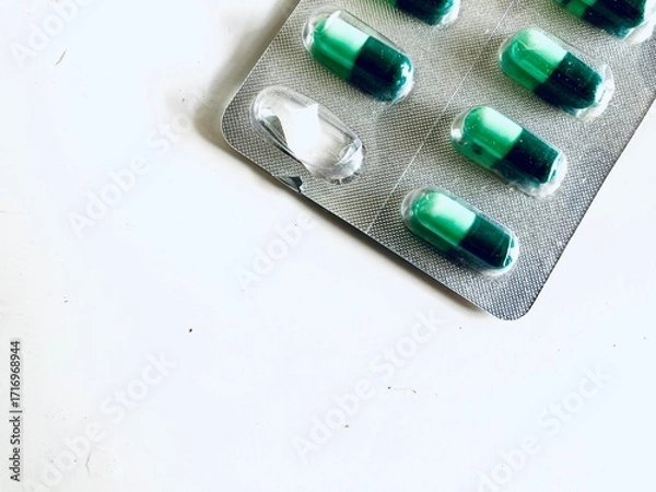 Fototapeta green capsules in a blister on a white background, with one capsule was already taken
