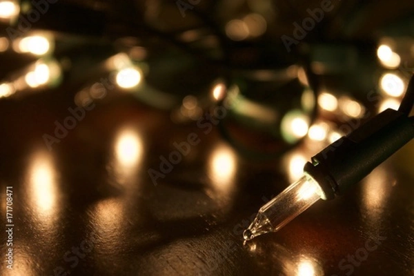 Obraz Christmas lights on the table getting ready to be put up. Bright white twinkly lights for the holidays. Christmas eve lighting decoration fun. Translucent xmas tree lights background. 