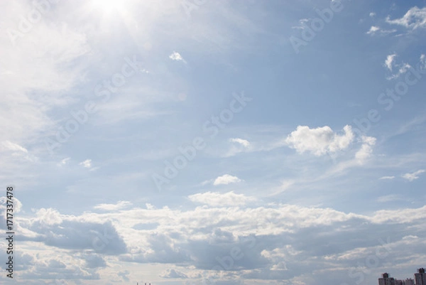 Fototapeta Blue sky background with clouds. High clear bright blue sky over the city with fluffy clouds on a sunny day