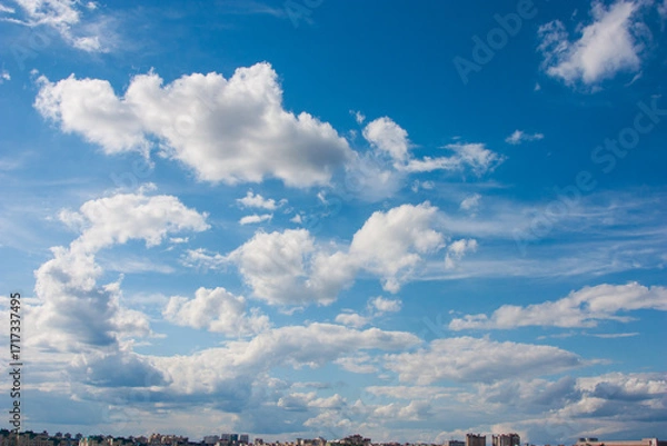 Fototapeta Blue sky background with clouds. High clear bright blue sky over the city with fluffy clouds on a sunny day