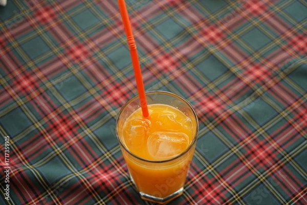 Fototapeta Glass of orange juice with straw close up – fresh citrus fruit drink on table, healthy beverage, vitamin C refreshment, natural summer cocktail background for diet, lifestyle and restaurant concept