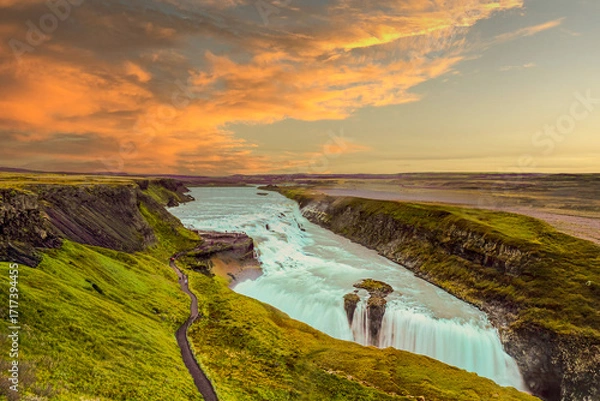 Fototapeta Golden hour view of Gullfoss waterfall in Iceland, October 2016, cascading white water through dramatic cliffs, colorful sky glowing above canyon, symbolizing iconic Nordic travel landscape.