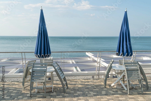 Fototapeta Relaxing Seaside View With Umbrellas and Tables on a Sunny Day