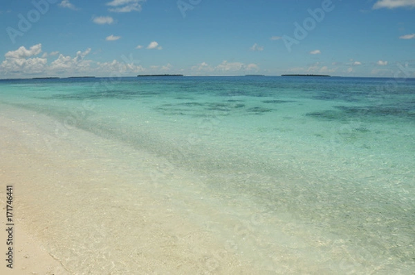 Fototapeta Crystal clear blue waters of the Indian Ocean, view from beach on golden sands in the Maldives