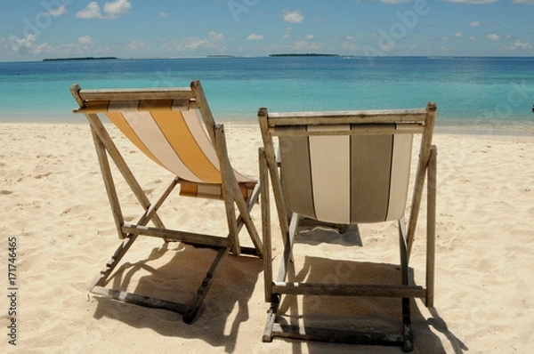 Fototapeta Two Beach chairs looking out to the beautiful blue Indian Ocean, sitting on golden soft sand in the Maldives