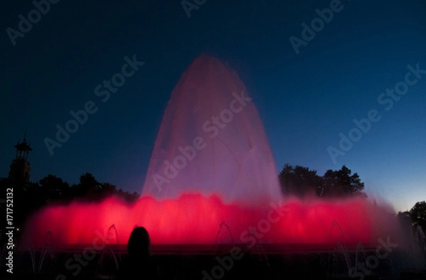 Fototapeta Silhouette of person taking a photo of a Large colourful Water Fountain display