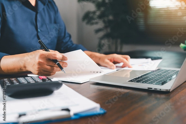 Fototapeta Office businesswoman hand to operate calculator analyzing financial data, counting costs on desk. accounting, financial analysis for business budget planning, calculation support, finance management.