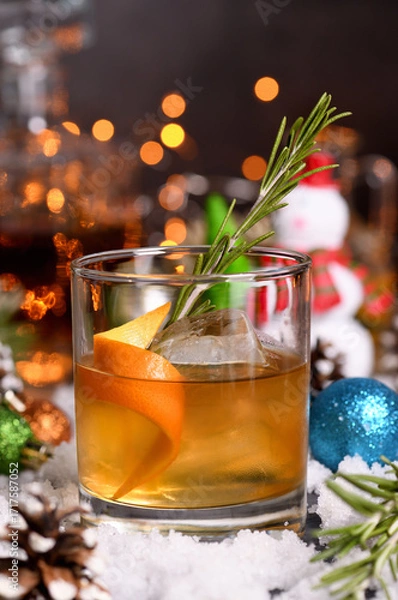 Fototapeta Spiced Bourbon Old Fashioned. Spicy rosemary, syrup, mixed with warming bourbon, fresh lemon and orange. Perfect for chilly evenings