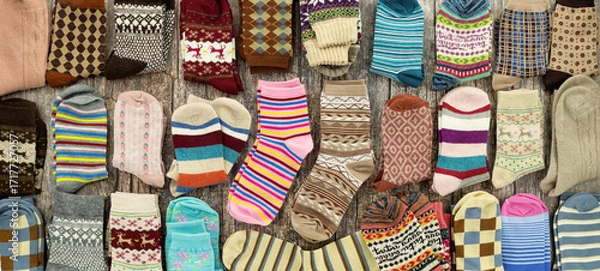 Fototapeta A pile of socks on a wooden background in a panoramic view. Lots of colorful socks for fall and winter.