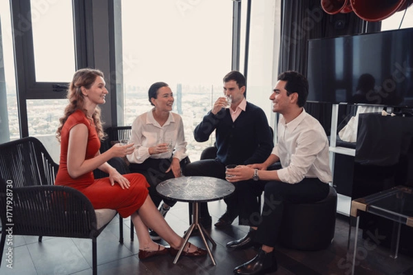 Fototapeta Group of business professionals having casual conversation and networking in modern office lounge with city view..