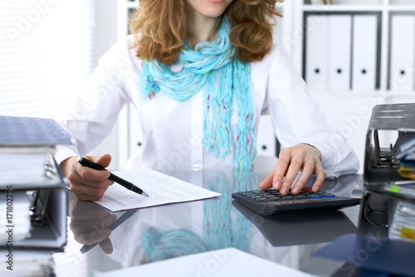 Obraz Female bookkeeper or financial inspector  making report, calculating or checking balance. Internal Revenue Service checking financial document. Audit concept