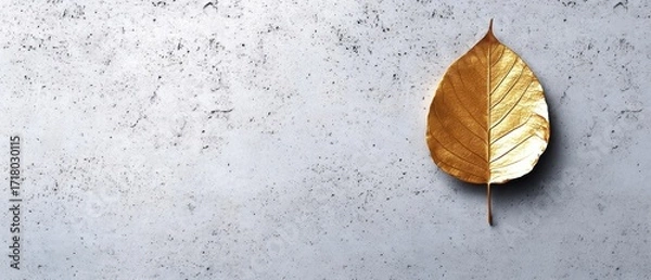 Fototapeta A Single Golden Leaf on a Textured Gray Concrete Background for Natural Beauty and Minimalist Design Concepts