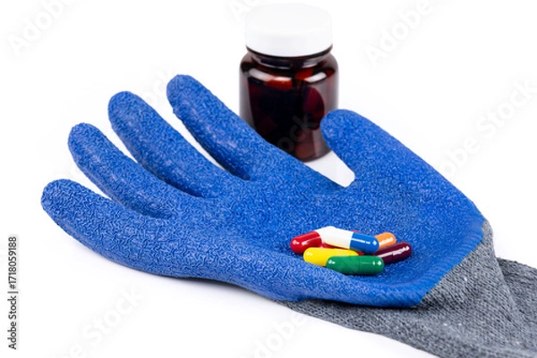 Fototapeta Blue protective glove with colorful capsules and medicine bottle isolated on white background with clipping path.