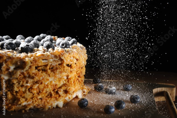Obraz Napalion cake, puff cake with blueberry sprinkled with powdered sugar, on a rough wooden backing, menu background