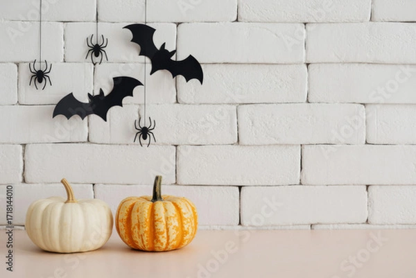 Fototapeta Modern spooky vignette with pumpkins, spiders, and bats on white wall background