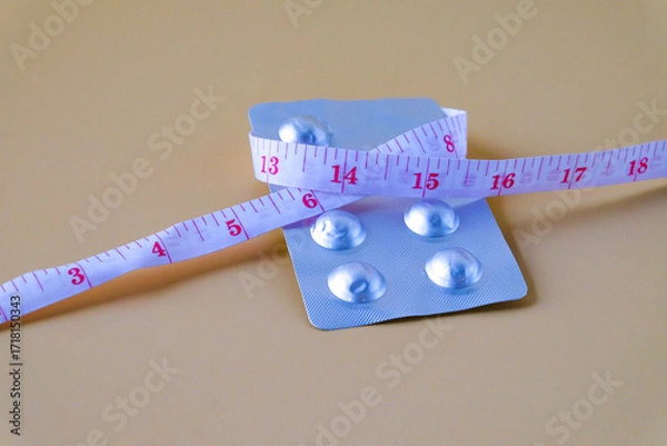 Fototapeta A pills and a measuring tape suggest a journey towards health.