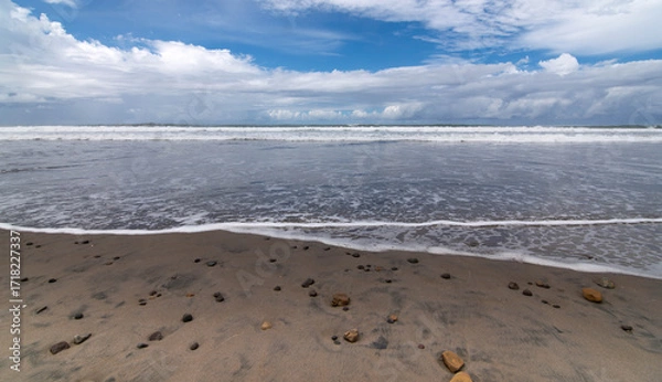 Fototapeta La espuma de las olas llegando hasra la orilla en un día soleado