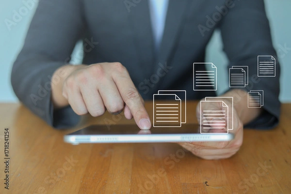 Fototapeta Businessman check report on tablet with digital document icons for online file management and cloud storage. Concept of data sharing, digital transformation, paperless office and business technology.