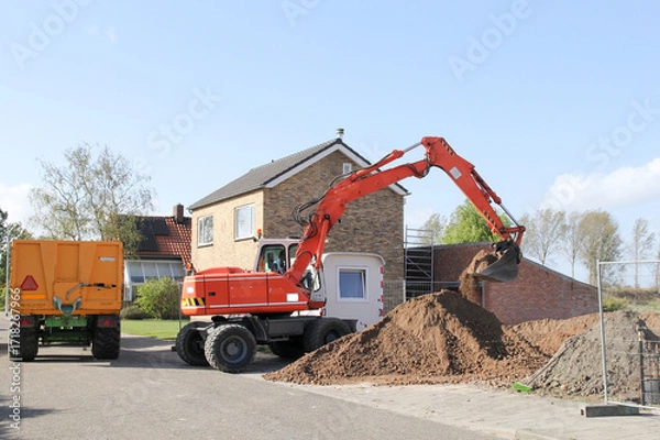 Fototapeta a construction site with heaps of ground and an excavator and a tipping trailer in the countryside