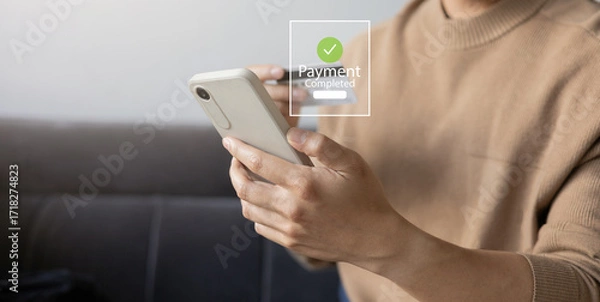 Fototapeta Close up hand using smartphone with payment completed message on screen. Mobile banking of online shopping and e-wallet transaction for digital finance and secure electronic payment concept