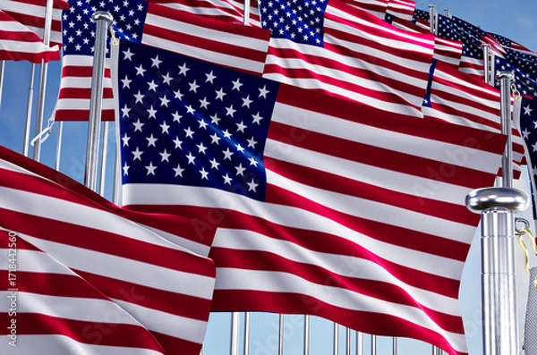Fototapeta united states of america many flags in row waving together on blue cloudy sky,