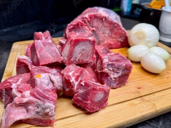 Fototapeta Carne em cubos cortas sobre a mesa com fundo desfocado e cebolas e panela con nivel de agua.