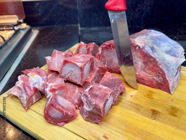 Fototapeta Carne em cubos cortas sobre a mesa com fundo desfocado e cebolas e panela con nivel de agua.