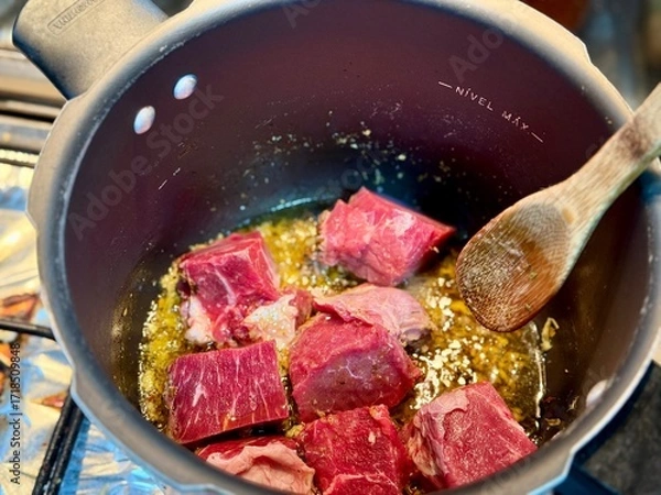 Fototapeta Carne em cubos cortas sobre a mesa com fundo desfocado e cebolas e panela con nivel de agua.