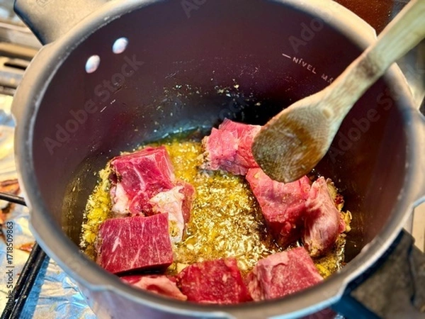 Fototapeta Carne em cubos cortas sobre a mesa com fundo desfocado e cebolas e panela con nivel de agua.