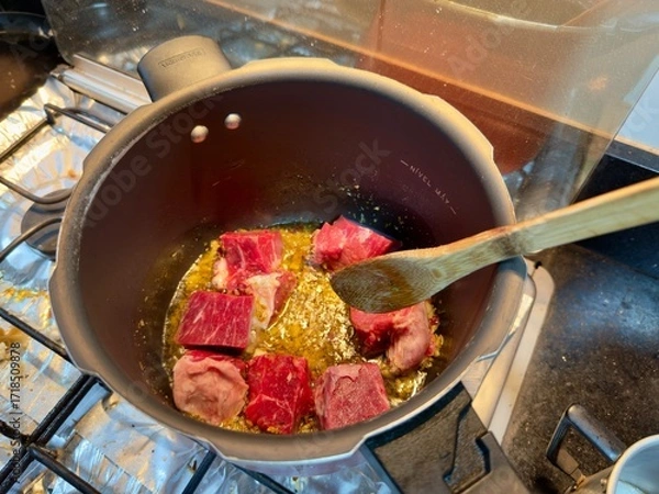 Fototapeta Carne em cubos cortas sobre a mesa com fundo desfocado e cebolas e panela con nivel de agua.